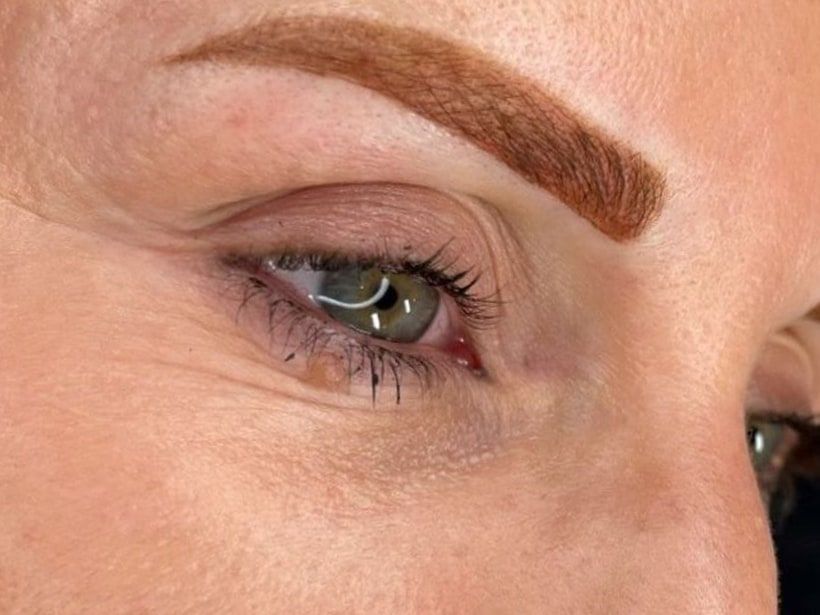 The same eyebrow straight after permanent makeup: a full, arched shape in warm brown.
