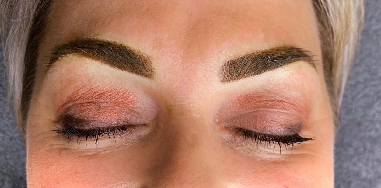 The same closed eyes straight after permanent makeup: defined, dark brown brows with a full tail.