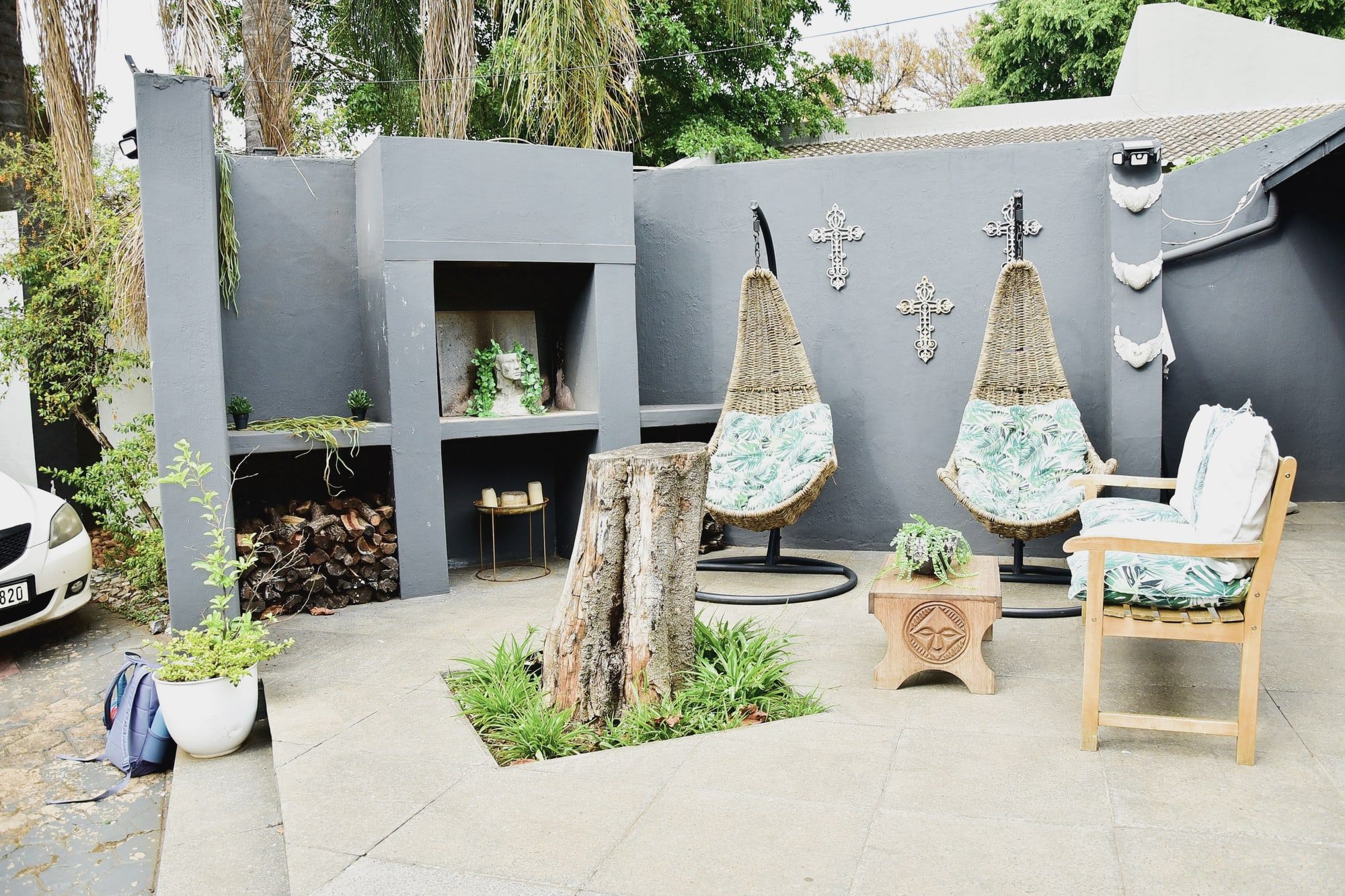 The paved courtyard outside the studio, with hanging basket chairs and a garden bench.